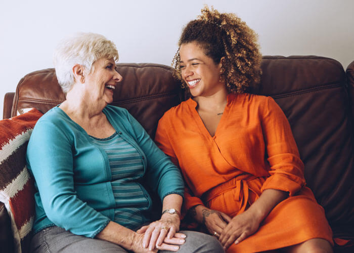 Caregiver and client sitting together and laughing