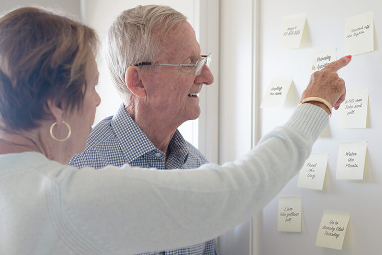 Elderly couple pointing and looking at sticky notes reminders