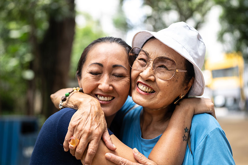 A woman hugging her mom is smiling because she has learned how to improve communication with someone with dementia.