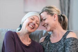 A woman offers support to a family member with cancer as they smile and enjoy spending time together.
