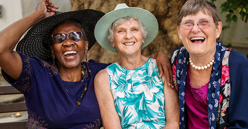 Three women share a laugh together, as their family members encouraged a more positive outlook for older loved ones.