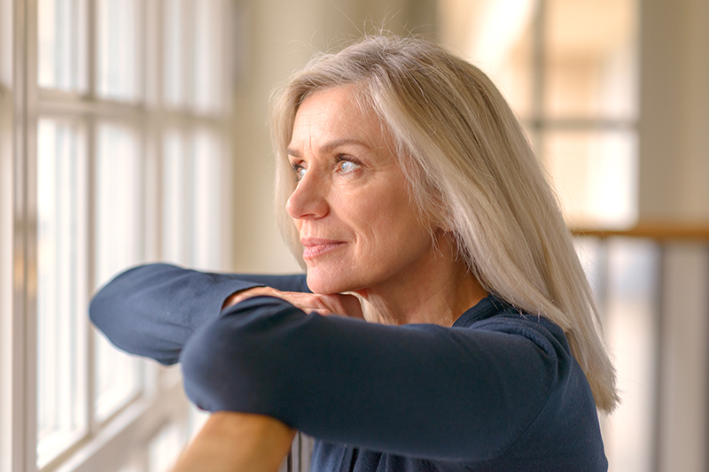 A woman practices taking a break and calmly looking out her window as a way of managing anger as a dementia caregiver.