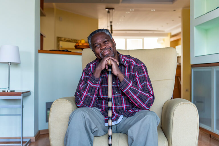 A man sits in a chair with his cane thinking about how sitting disease in older adults can cause health complications.