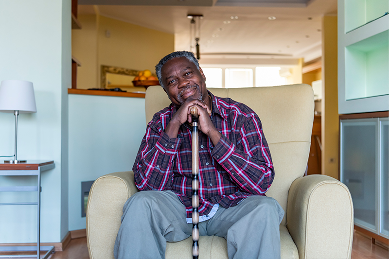 A man sits in a chair with his cane thinking about how sitting disease in older adults can cause health complications.