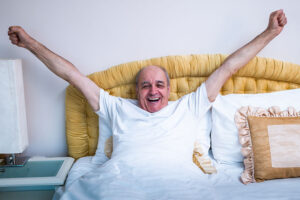 A man stretches while waking up well rested because he found senior sleep solutions that work for him.