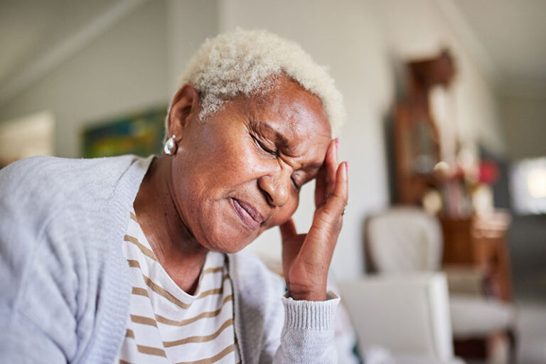 A woman experiencing COPD headache symptoms closes her eyes and clutches her head.