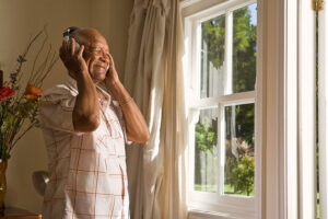 A senior man listens to music on headphones to get his favorite song in his mind for a Parkinson’s mobility exercise.