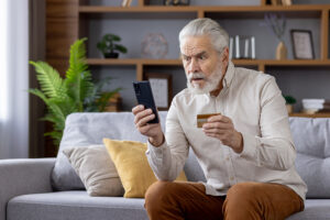 A man who has is building his senior scam awareness notices something fishy on his phone.