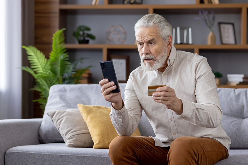 A man who has is building his senior scam awareness notices something fishy on his phone.