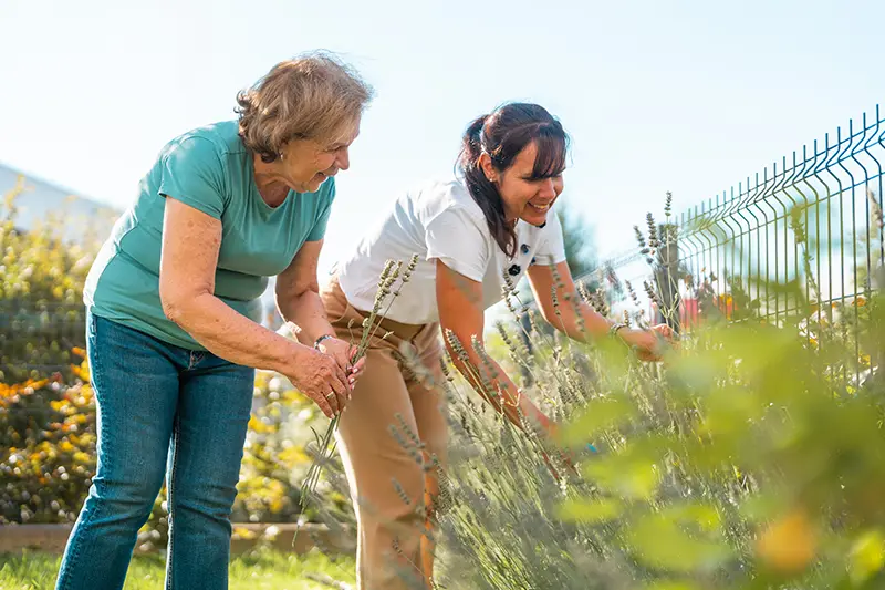 A happy older woman enjoys retirement activities for moms, like gardening, that inspire connection and well-being.