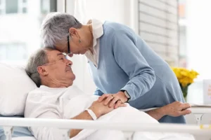 A wife offers reassurance to her husband as he receives dementia hospital care.