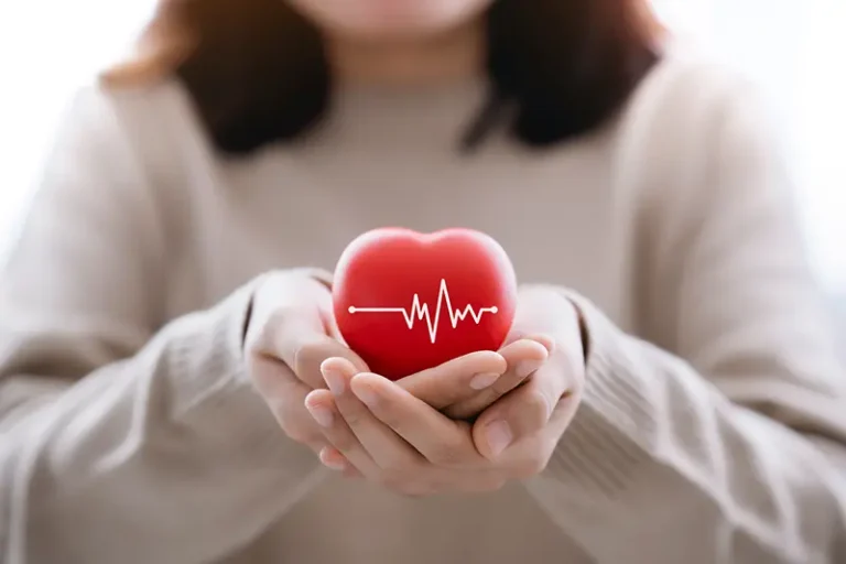 A woman holds a small heart-shaped object to raise awareness of heart disease in older women.