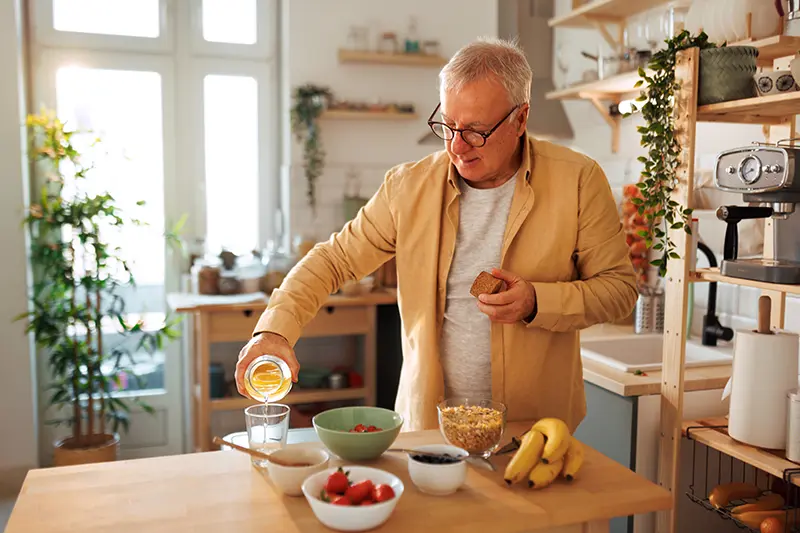 A senior man makes a meal for himself as he thrives at maintaining independence with dementia.