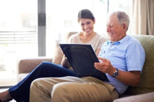 An older adult looks through a photo album with his daughter, demonstrating the benefits of reminiscing for seniors.
