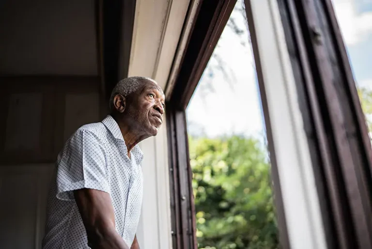 A senior man stares out the window after practicing some exercises designed for helping someone with dementia wait calmly.