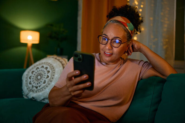 A woman struggling with family caregiver burnout stays up too late scrolling on her phone.