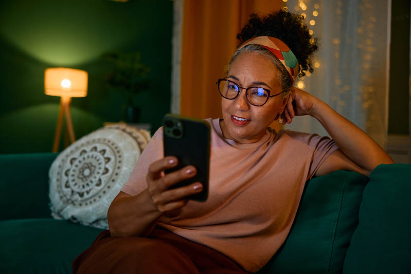 A woman struggling with family caregiver burnout stays up too late scrolling on her phone.
